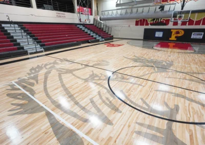 School gymnasium red bleachers with maple floor and grey hoarse graphics and gym equipment installed by BROC